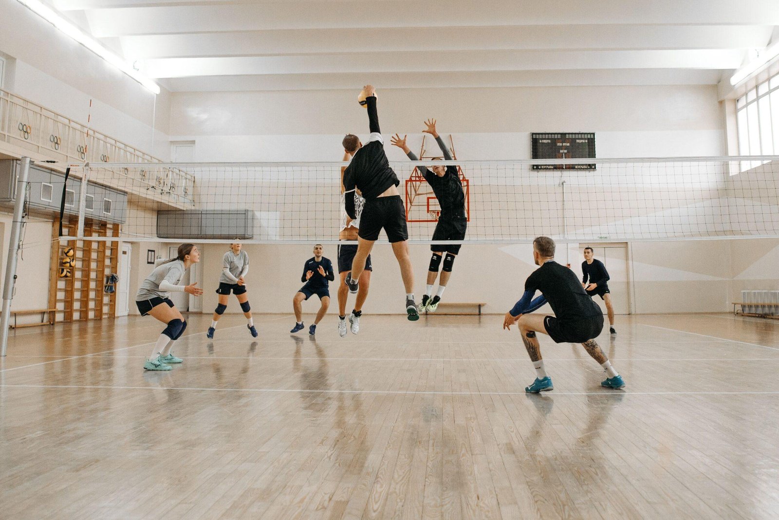 jeu entre deux équipes avec un joueur de dos en train de smasher et l'équipe adverse qui se prépare à recevoir